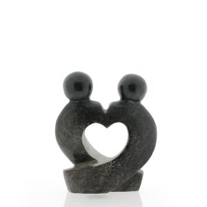 Een spekstenen beeldhouwwerk in donkere steen, dat twee personen toont die elkaar liefdevol vasthouden, waardoor een hartvorm ontstaat. Dit kunstwerk is met de hand vervaardigd in Zimbabwe en straalt warmte en verbondenheid uit.